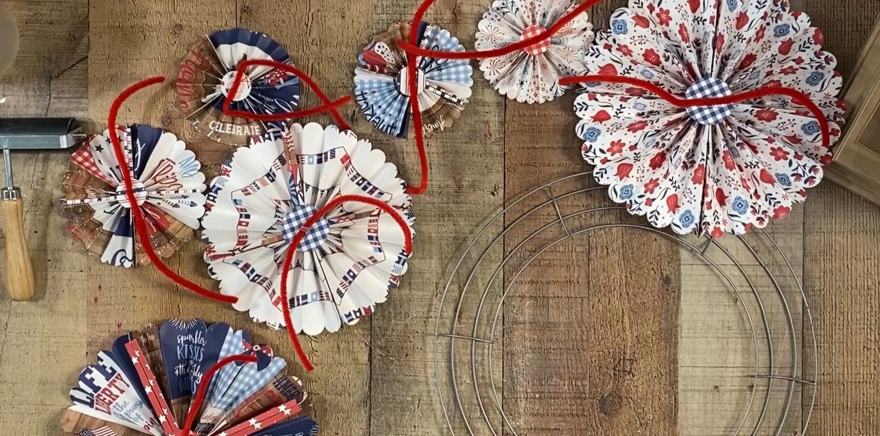 All rosettes on a table with pipe cleaners glued to the back next to a wreath frame.