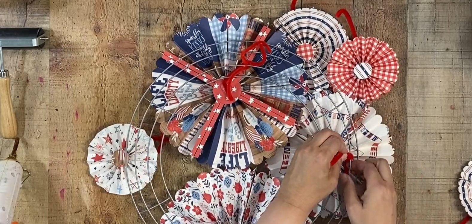 Rosettes with pipe cleaners being attached to wire frame.